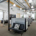 Second-floor open office layout featuring high-end workstations and abundant natural light.